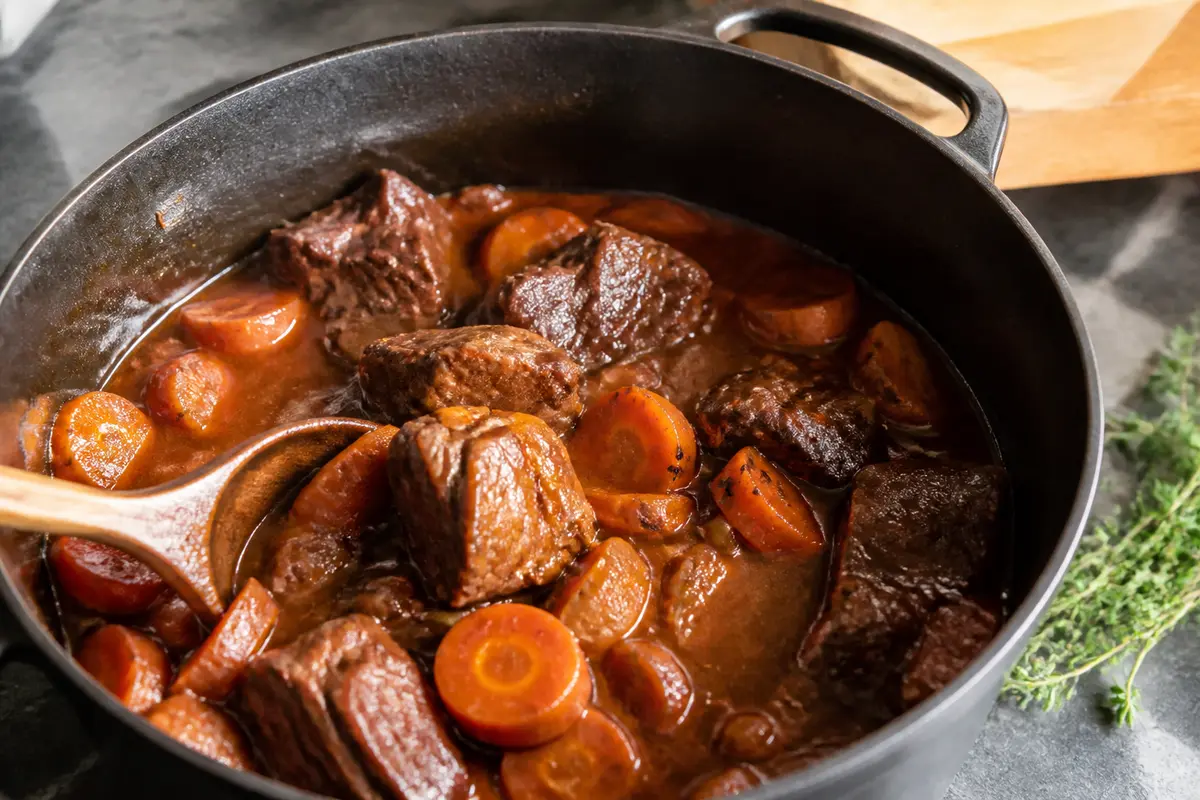 Plat de boeuf braisé aux carottes dans une cocotte en fonte brun foncé