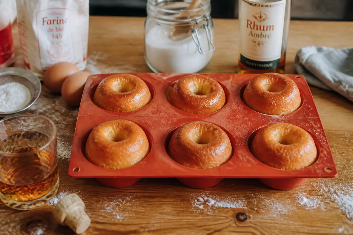 Pâtisseries dans un moule à baba au rhum rouge avec ingrédients autour sur la table