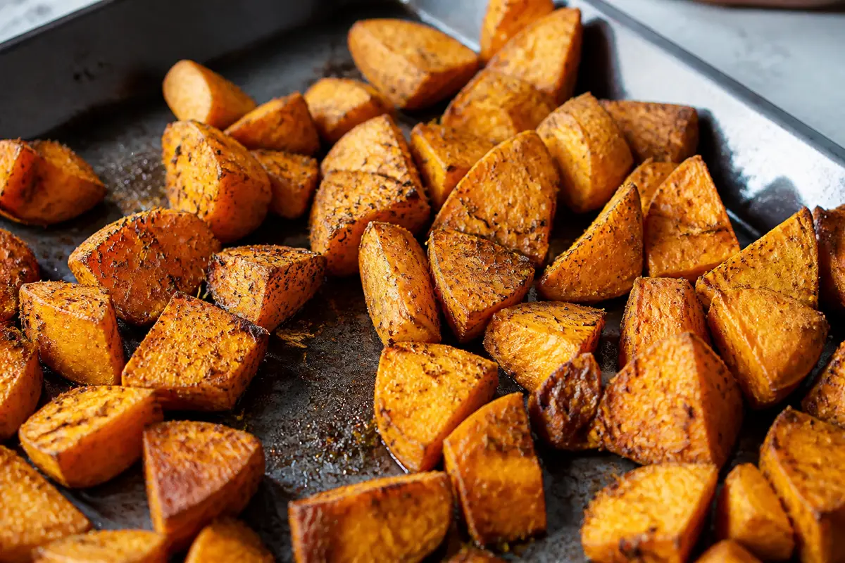 Morceaux de patate douce rôtie au four disposés sur une plaque de cuisson.