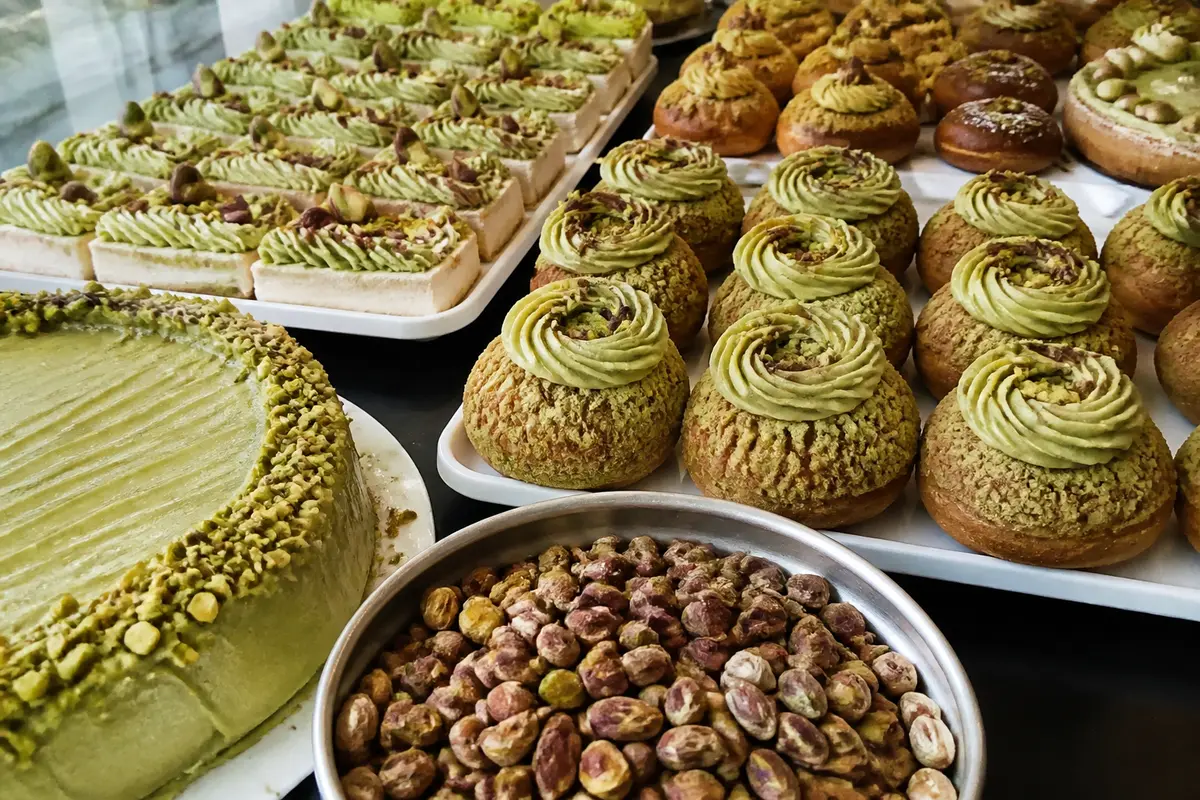 Assortiment de pâtisseries à la pistache avec tartelettes, choux, et pistaches entières affichées